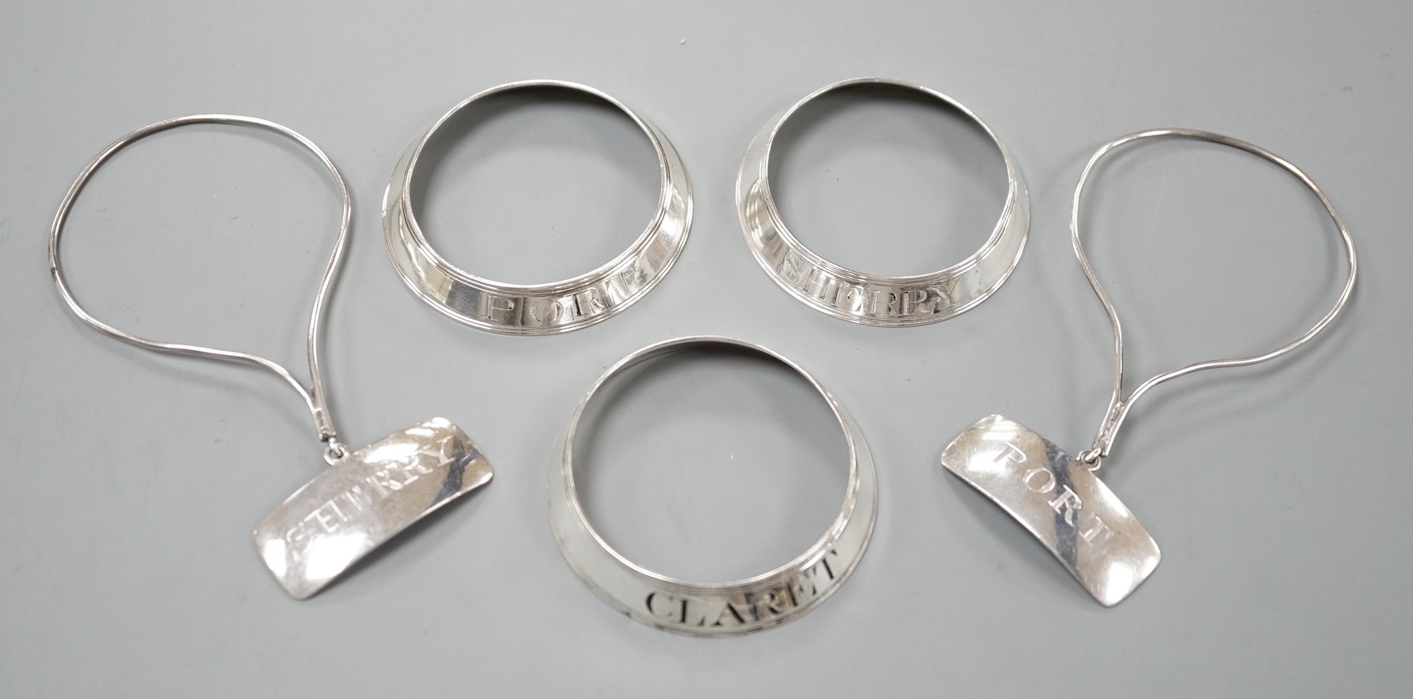 A set of three George silver decanted wine collar labels, Robert Barker, London, 1793 and a pair of similar silver wine label collarettes by Peter & Ann Bateman, London, 1798.